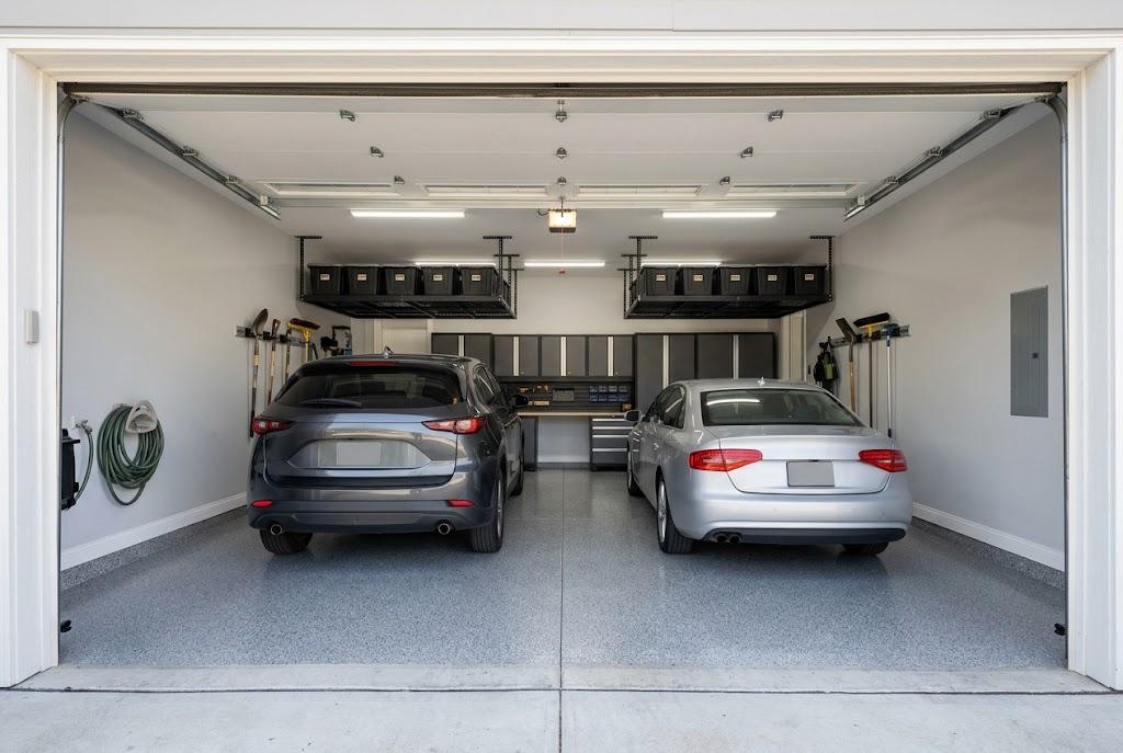 Two cars parked in an organized garage with overhead storage racks, rear-wall cabinets and wall-mounted tools.